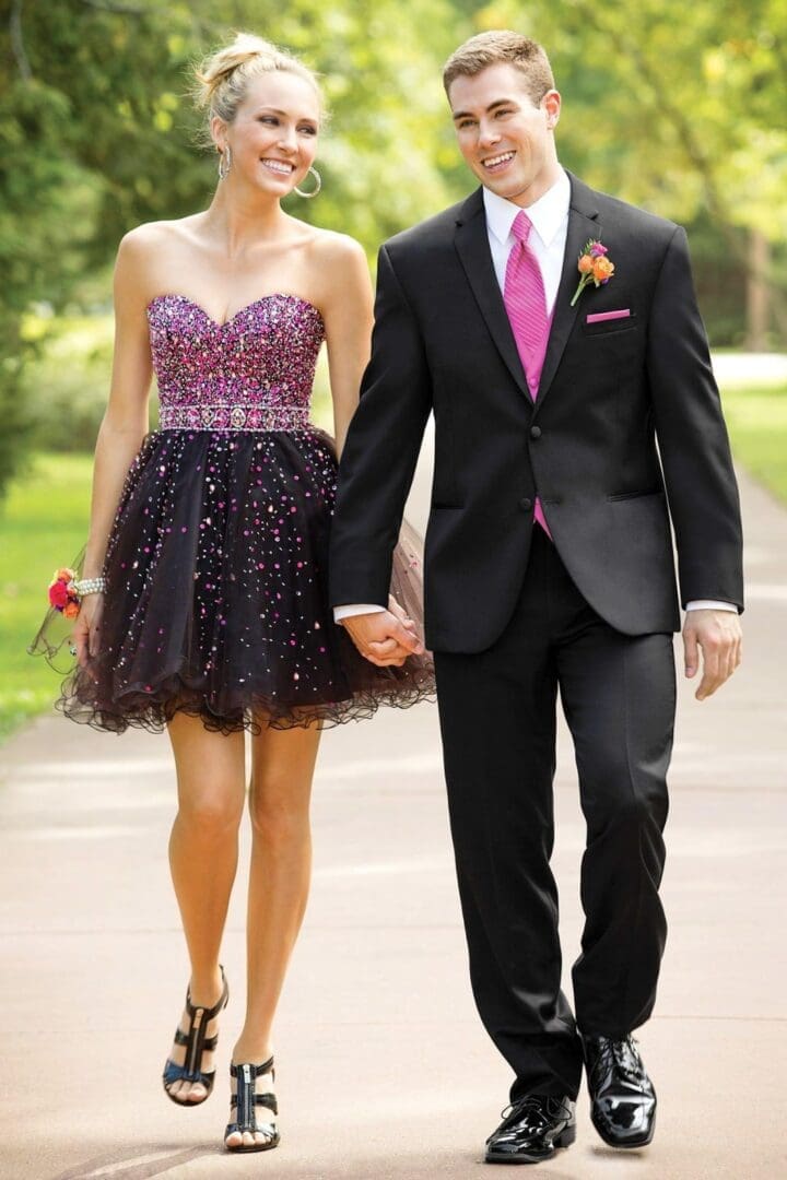 A man and woman holding hands while walking down the street.